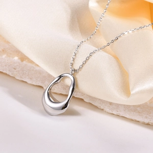 Minimalist irregular oval pendant necklace in silver finish on silk and stone background