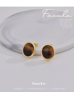Close-up of vintage gold earrings with oval tiger eye stones on marble background