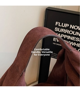 Detail of the wide handle on a dark reddish-brown suede tote bag with matte finish
