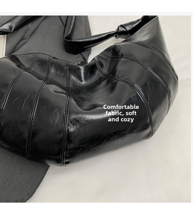 Detailed close-up of quilted black crescent bag with glossy texture and knotted strap
