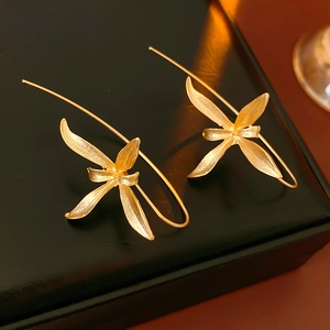 Close-up of golden iris flower leaf earrings with textured finish on a jewelry box