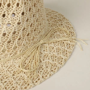 Detail of breathable hollow weave straw hat with beige ribbon bow for summer sun protection