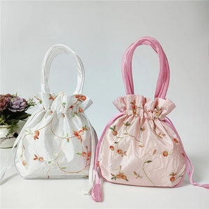 Detail of embroidered floral patterns on white and pink drawstring silk bucket bags