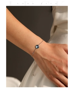 Détail d'un bracelet en argent S925 avec cristal bleu clair porté au poignet d'une femme
