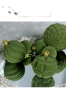 Close-up of dark green flocked Christmas balls with textured patterns and gold metal hooks