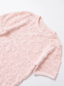 Détail de maille rose pelucheuse montrant la texture douce et le col rond côtelé