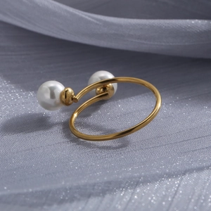 Close-up of gold plated stainless steel ring with double pearls on grey fabric