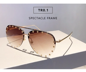 Detail of semi-rimless sunglasses with gold studs and brown gradient lenses