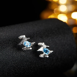 Macro detail of silver earrings featuring oval light blue topaz in geometric frames