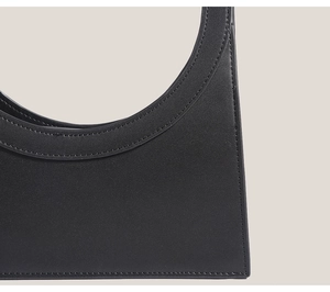 Close-up of fine leather texture and precise stitching on the black ring handbag
