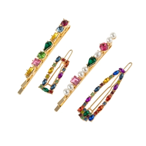 Détail d'un ensemble de quatre barrettes dorées avec strass colorés et perles d'imitation