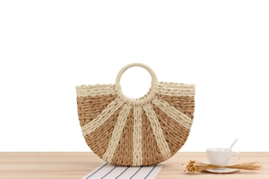 Detail of semi-circular straw tote featuring two-tone woven texture and round handles