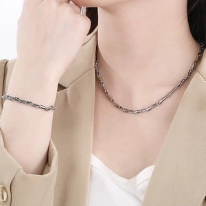 Detail shot of a silver titanium steel geometric link necklace and bracelet set on a model