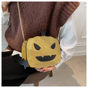 Close-up of glittery pumpkin crossbody bag with gold chain and black bat charm