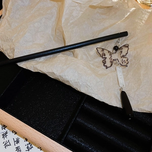 Detailed close-up of a vintage hair stick featuring a translucent butterfly and water drop tassel