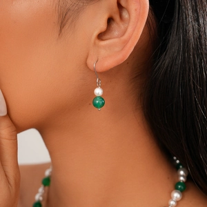 Detail of green agate and white pearl earrings on model with matching necklace