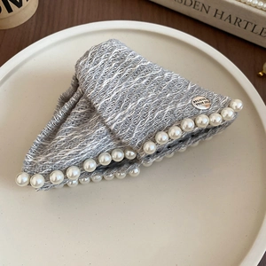 Detail of grey tweed hair claw clip with cream pearls and engraved metal plate tag