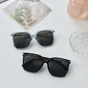 Detailed view of square frame sunglasses featuring decorative gold chain on black frames