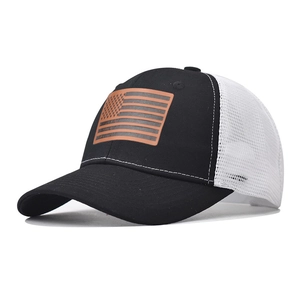 Dettaglio della toppa in pelle bandiera USA su cappello trucker mesh bianco e nero