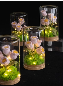 Dettaglio bouquet di tulipani rosa all'uncinetto con luci LED in cupola di vetro e base in legno