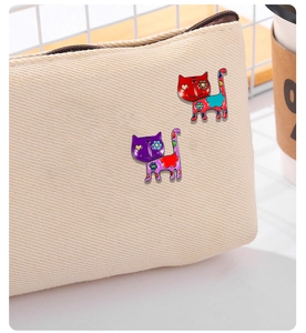 Detailed view of colorful cartoon cat pins on canvas bag showing enamel metal craft