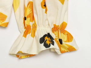 Detail of ruffled elastic cuffs with orange floral print on lightweight woven fabric
