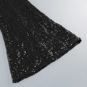 Detailed view of the black sequined fabric showing intricate texture on the flared sleeve