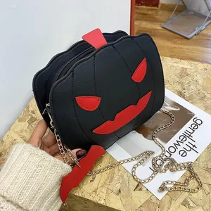 Close-up of novelty pumpkin crossbody bag with bat wing details and gold chain strap