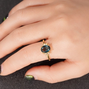 Macro detail of luxury oval blue gemstone ring with rectangular side stones on model