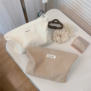 Close-up of striped cotton makeup bag with a Simple Wish woven label on a white surface