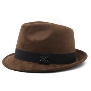 Detailed macro view of a dark brown suede fedora featuring a black band with a silver M logo