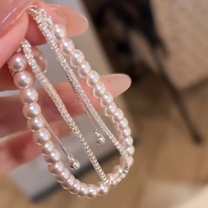 Macro shot of layered pearl and rhinestone bracelet on wrist with elegant silver chains