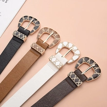 Detail of colorful faux leather belts with gold mesh horseshoe buckles on pink background