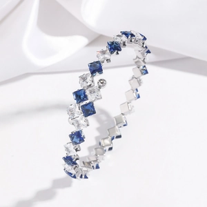 Detail of silver open bangle with square-cut blue and white cubic zirconia on silk