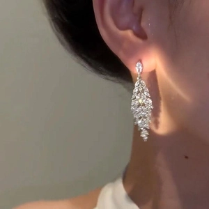 Elegant silver tassel earrings with zircon leaf design worn by a model in soft light