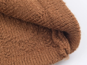 Vista macro del tessuto a maglia a coste marrone con fibre di lana morbide e trama