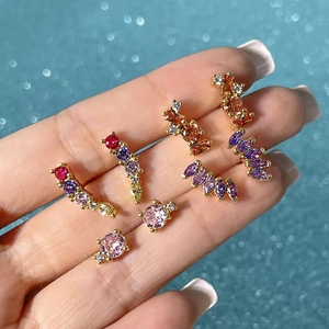 Macro shot of colorful zircon earrings in gold finish against a sparkling blue background