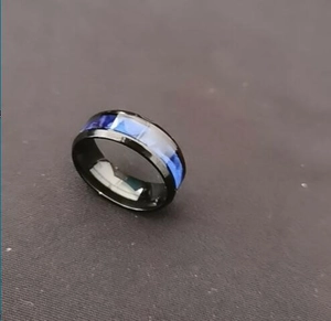 Macro detail shot of a fashion men's black titanium steel ring with iridescent blue inlays