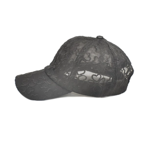 Detail of breathable black lace baseball cap featuring hollow heart patterns and curved brim
