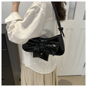 Detail of black hobo bag with a large decorative bow and knotted shoulder strap