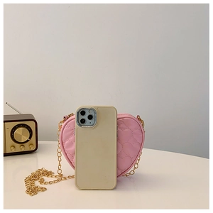 Pink heart-shaped crossbody bag with quilted PU leather and gold chain beside a phone