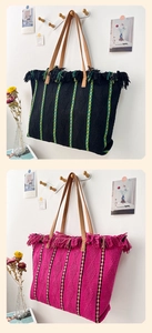 Detail of woven straw beach tote bags with colorful stripes, tassels and leather handles