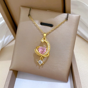Detailed close-up of a gold heart and moon pendant necklace featuring pink gemstones
