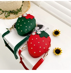 Detail of strawberry shaped crossbody bags in red and green with gold chain straps