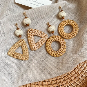 Detail of bohemian handmade woven rattan earrings in triangle and round shapes with gold hooks