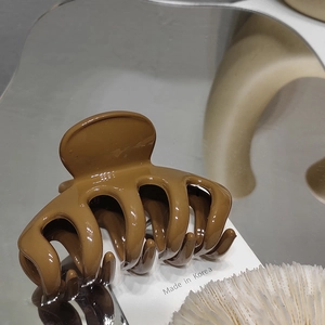 Macro shot of dark brown resin shark hair claw clip with Made in Korea text detail