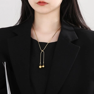 Adjustable golden snake chain necklace with bead charm shown on a female model