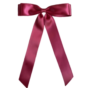 Close-up of elegant wine red satin ribbon double bow hair clip with long flowing streamers