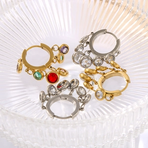 Detail of colorful zircon tassel hoop earrings in polished gold and silver finishes
