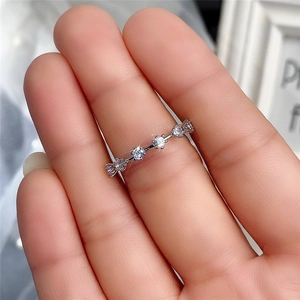 Nahaufnahme eines weißgoldenen Rings mit fünf runden Zirkonia-Steinen, am Finger getragen